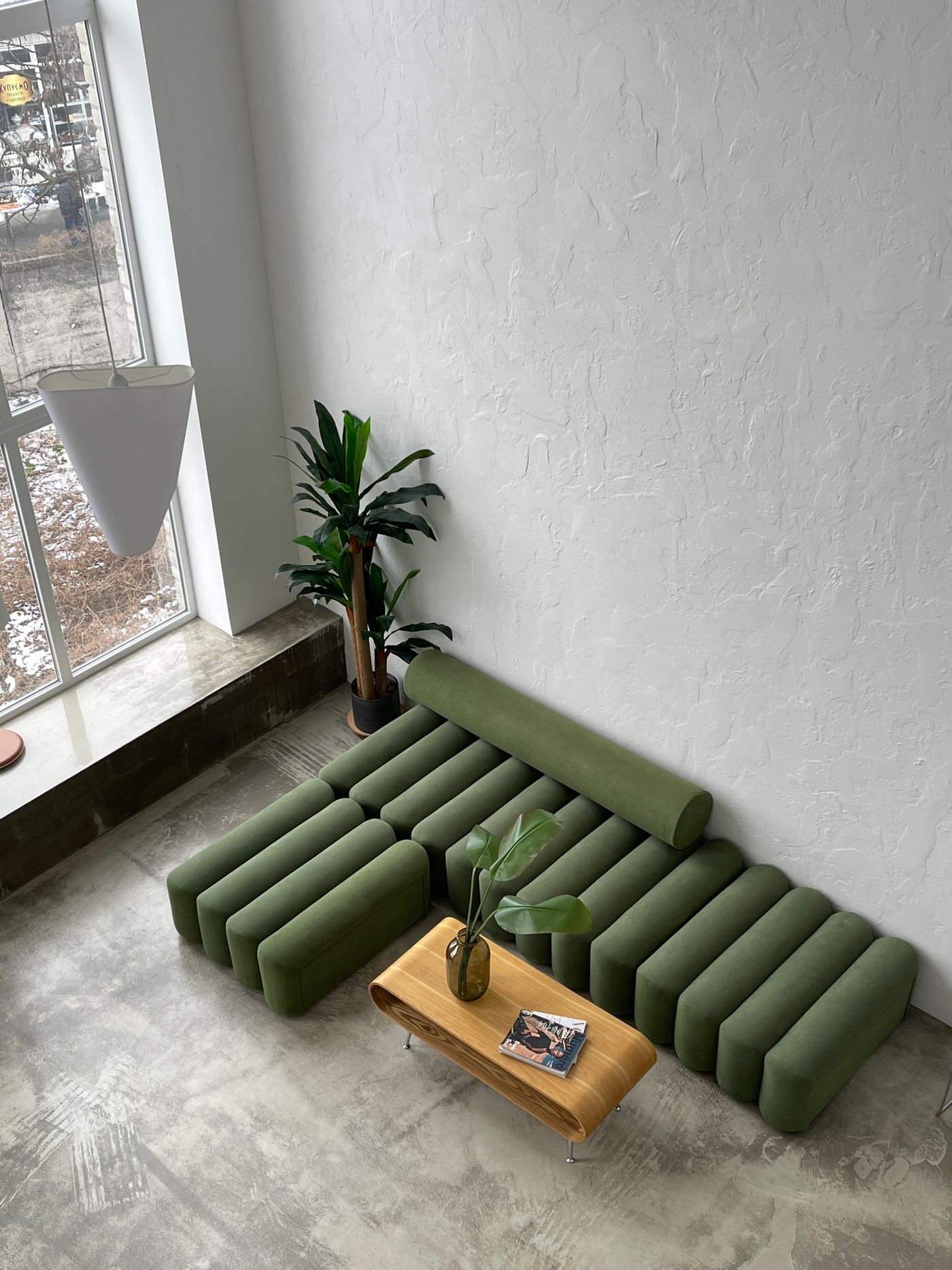 Sala residencial contemporânea com pavimento mineral visível e sofá verde